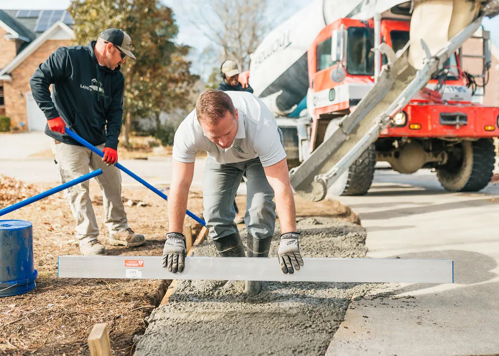 Daniel, owner of Magnolia Concrete, leveling freshly poured concrete on a residential driveway
