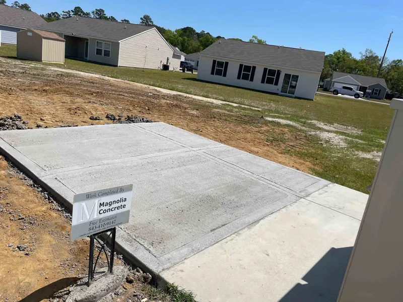 Completed backyard concrete patio with a Magnolia Concrete yard sign