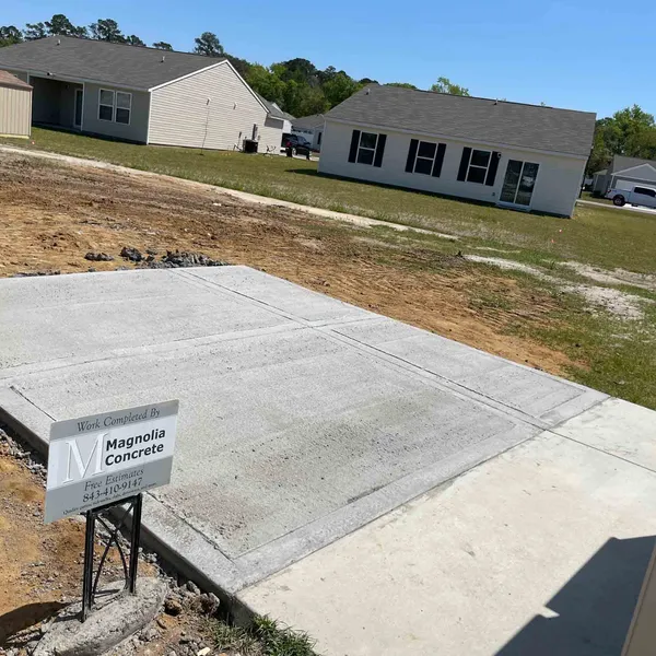 Completed backyard concrete patio with a Magnolia Concrete yard sign